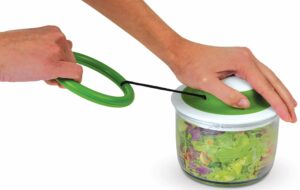 Chef'N Veggie chopper with a clear bowl with blade assembly and a top with a pull cord to cause the chopping motion of the blades.