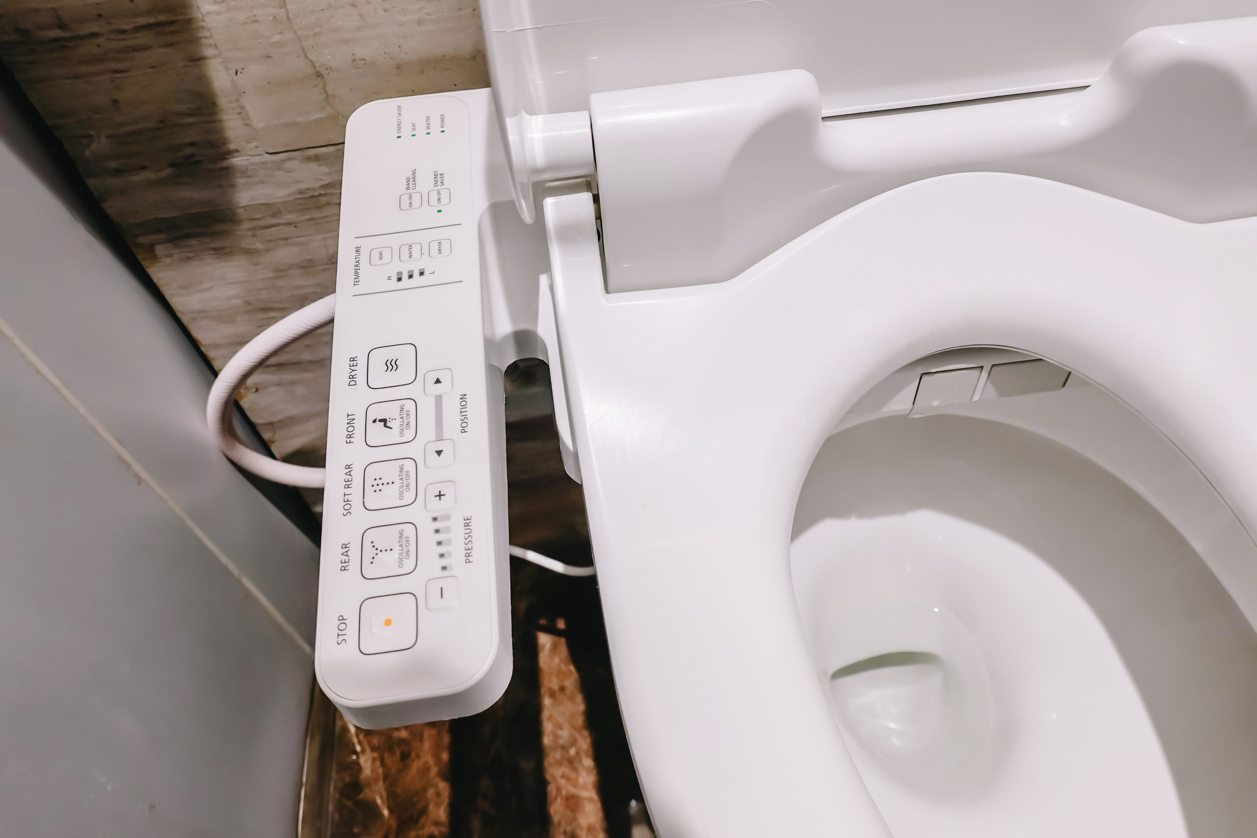 A bidet seat with arm controls the options on the arm controls read: stop, rear, soft rear, front, dryer
