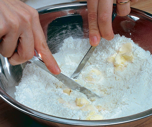Hand cutting butter into flour using 2 butter knives